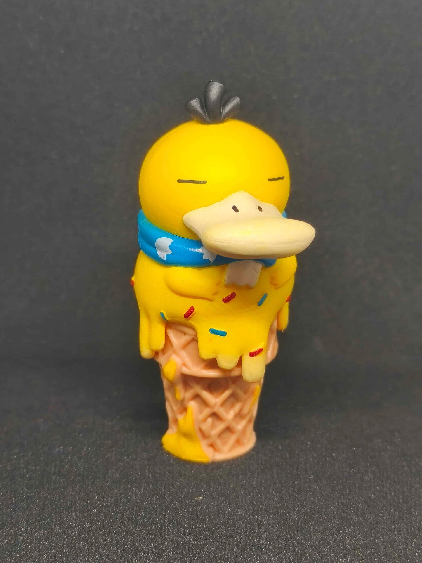 Figurine Psykokwak Pokémon en forme de glace sur fond noir, style kawaii, objet collection.
